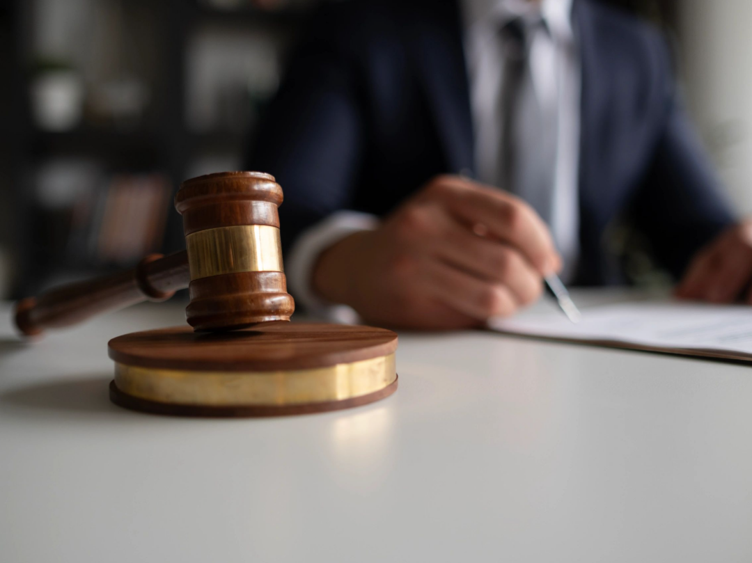 Expert Witness Matching Services gavel on desk with person in suit in the background