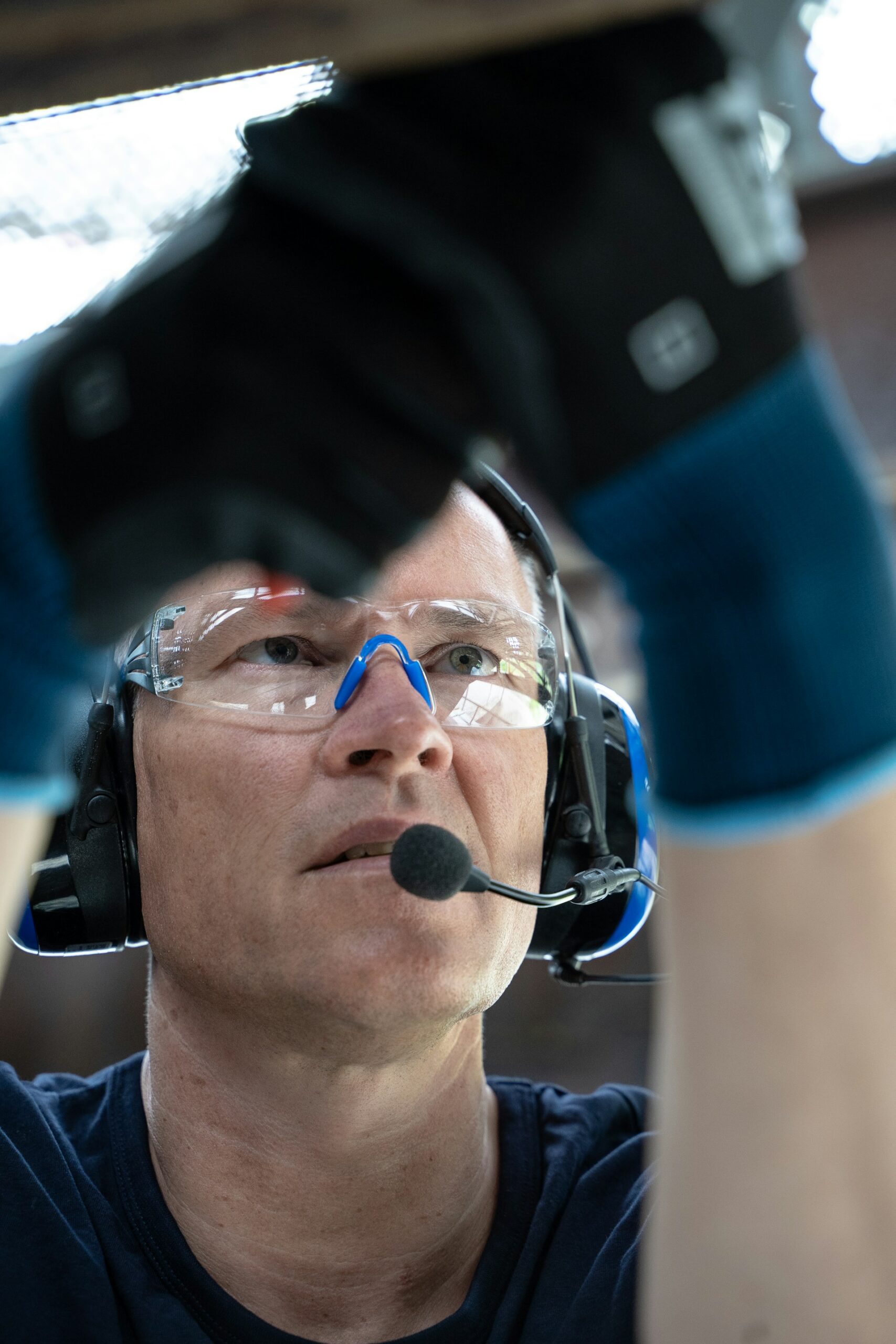 ear protection headset and eye protection goggles on man in industrial setting