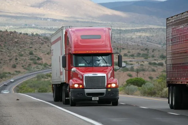 red semi-truck about to pass another semi-truck possible collision in a few moments