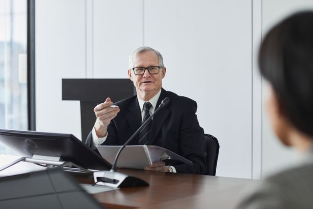 estate and trust expert witness older man at microphone at desk
